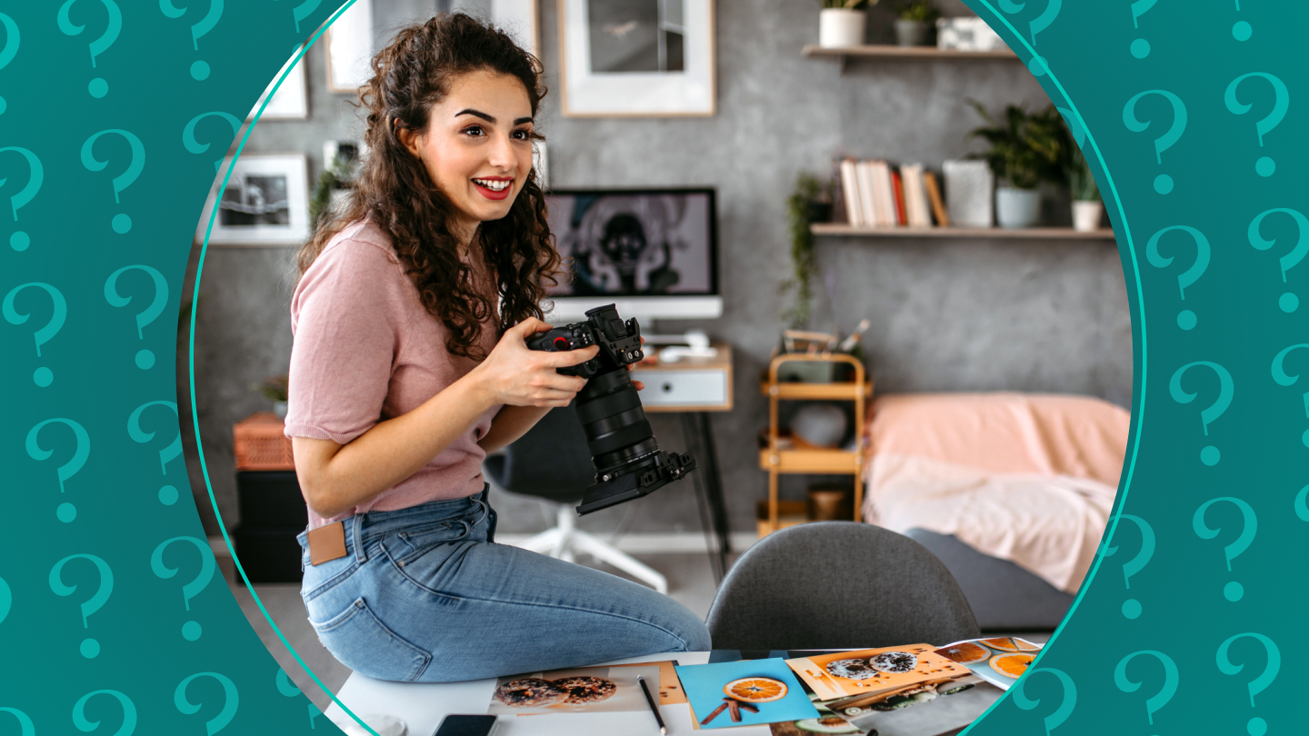 Woman sits on desk with camera in hand